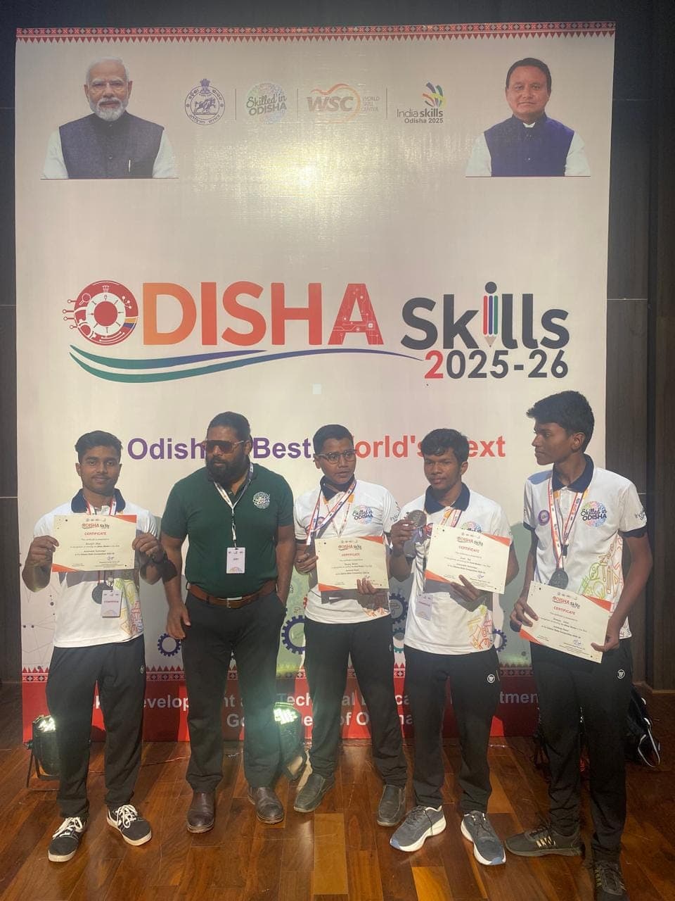 Founder with students holding certificates and medals at Odisha Skills 2025-26